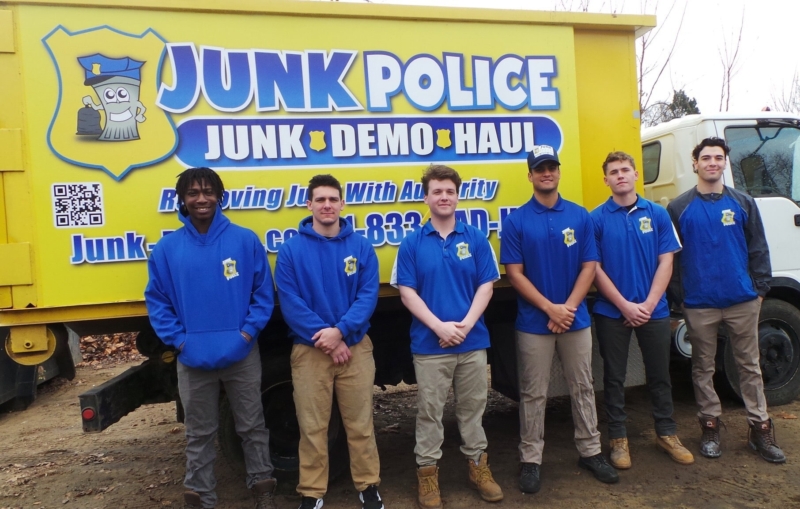 Junk Police professionals smiling next to their truck ready to provide junk removal services in Chester, PA